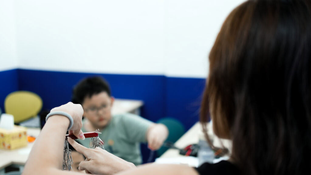 A close-up lifestyle shot of a teacher doing a science experiment on magnetism in a class setting.